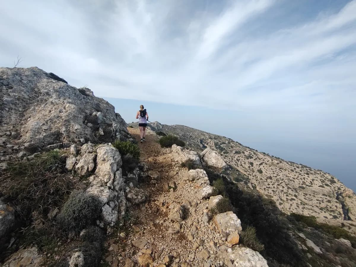 Runner on a rocky coastal ridge trail above the sea
