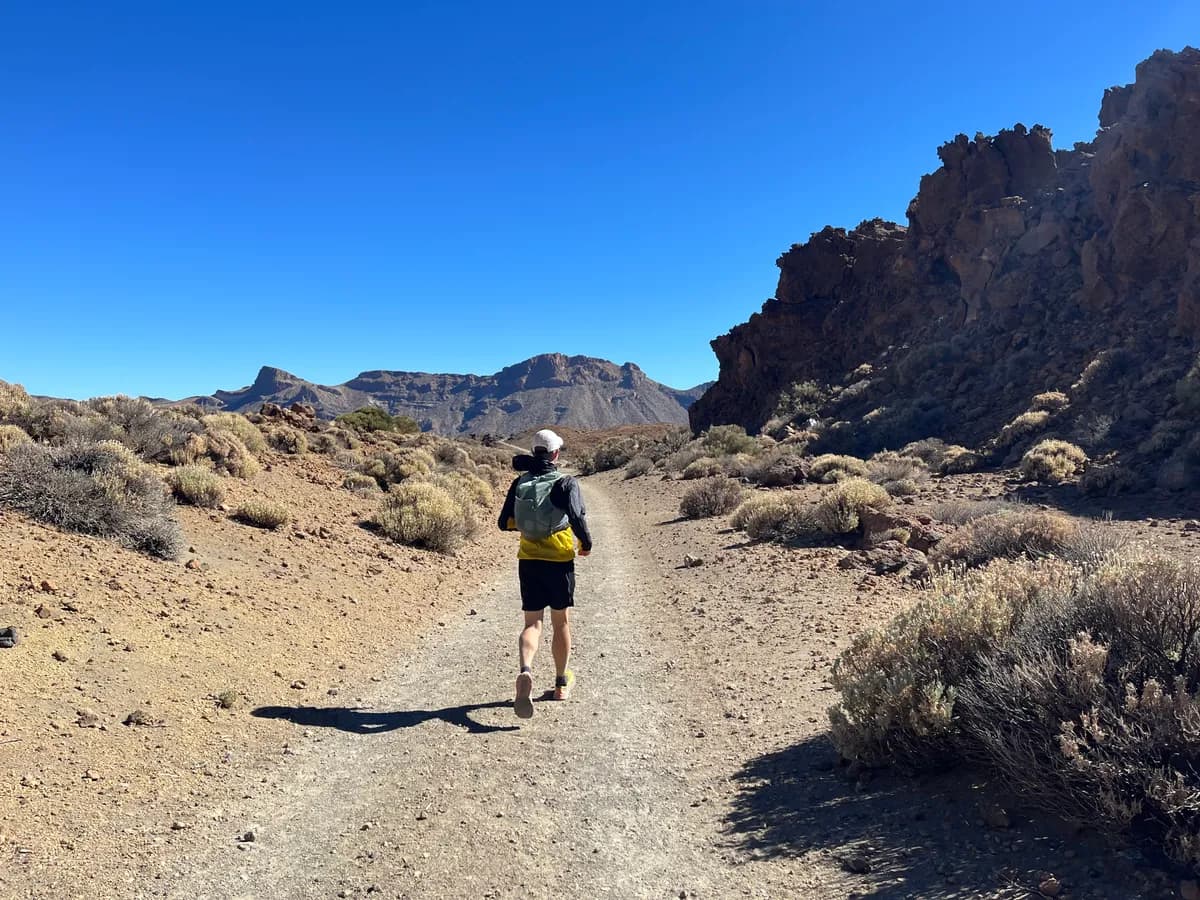 Runner on a dry volcanic trail with Teide peak in the background